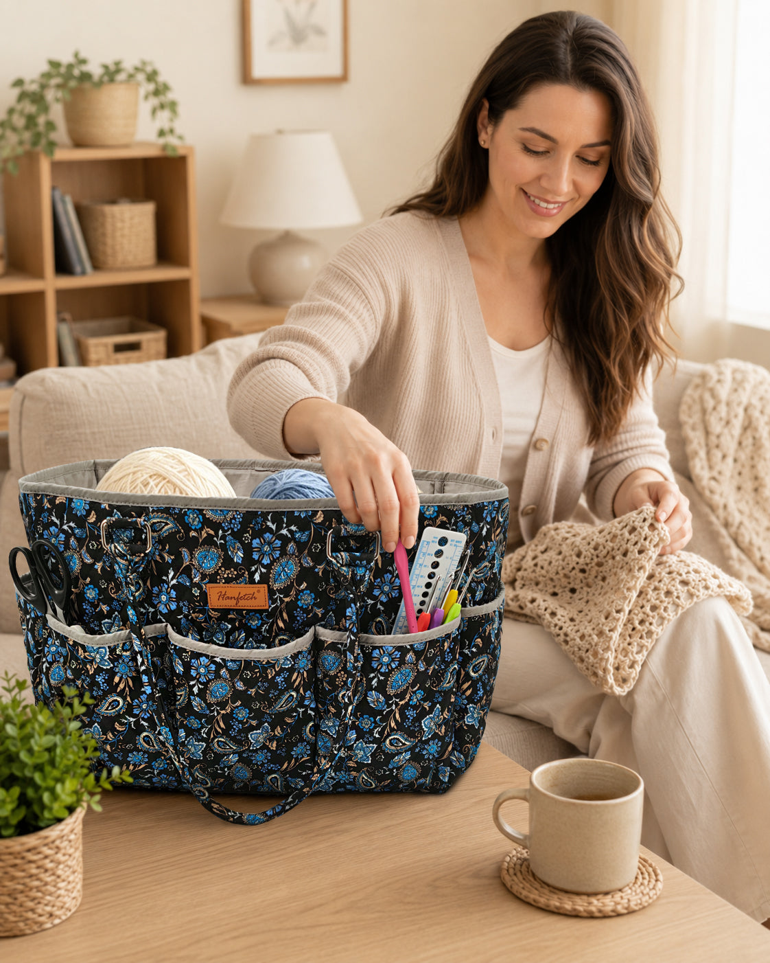 A maker reaching for a crochet hook from the quilted tote beside her current project