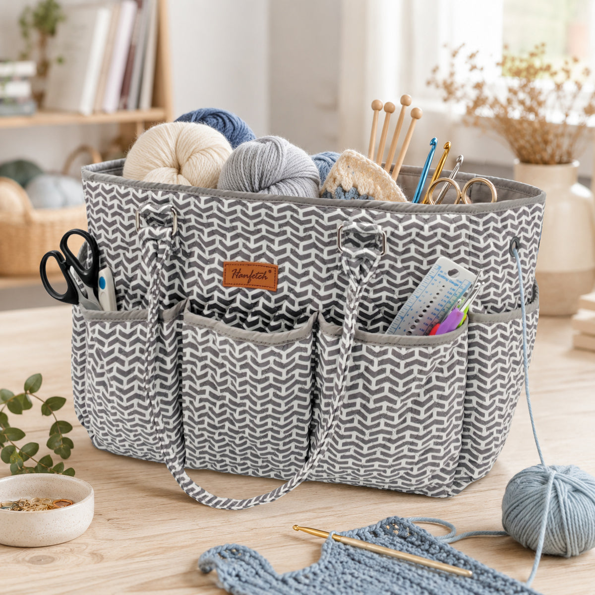 Grey arrow-pattern quilted yarn tote, shown holding yarn, knitting needles and crochet tools