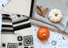 Ivory granny square crochet scarf displayed with knitted blankets and pumpkins in a cozy setting